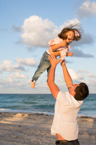 Father throwing daughter in air Miami Beach sunset