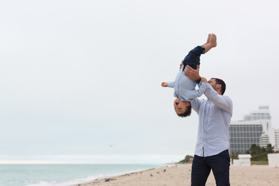 father holding son upside down on beach
