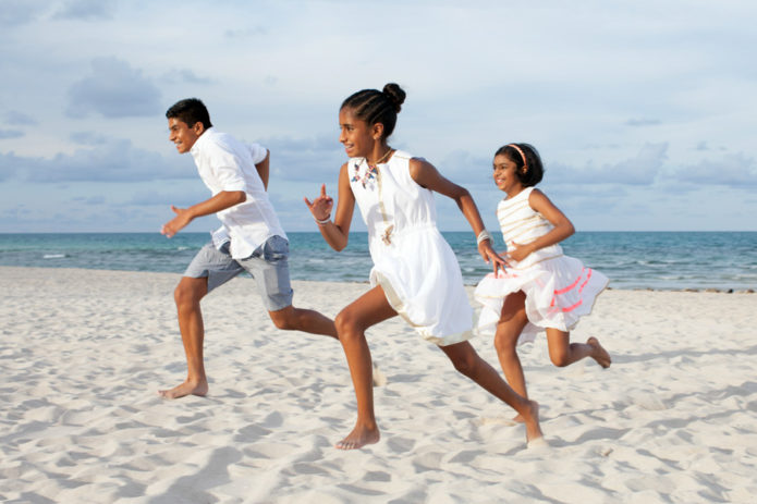 siblings running on beach