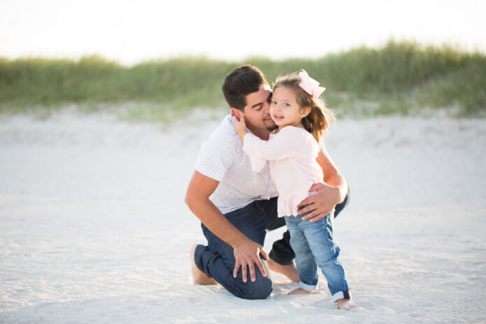 father embracing daughter on beach