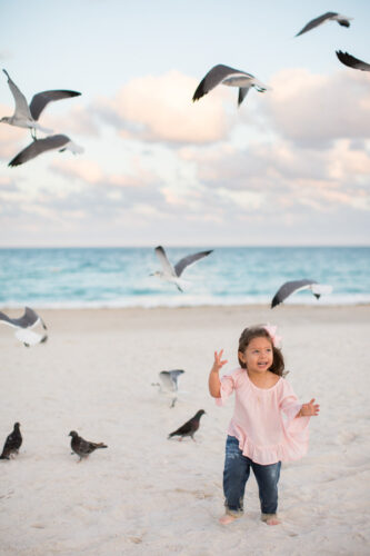 girl chases birds on miami beach