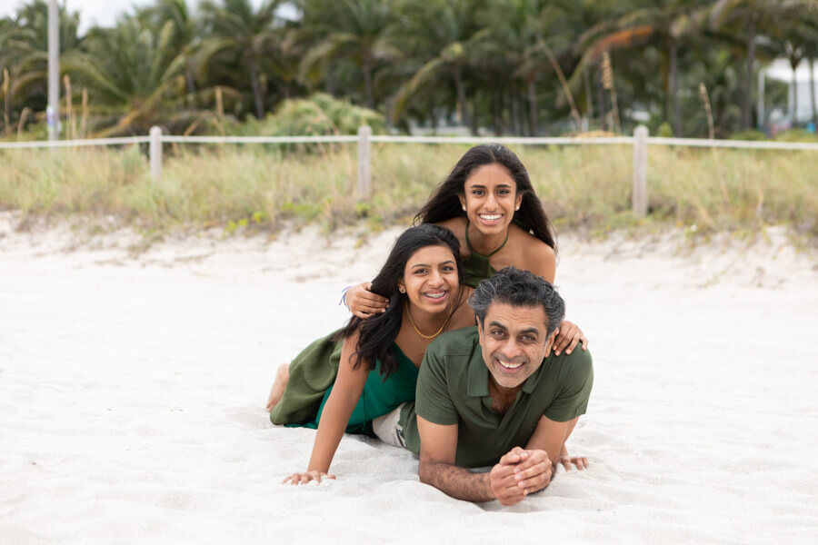 father with daughters lying on sand in miami beach