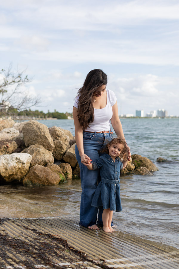 mother holding daughter's hand by the water