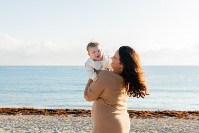 mother smiling at baby on beach