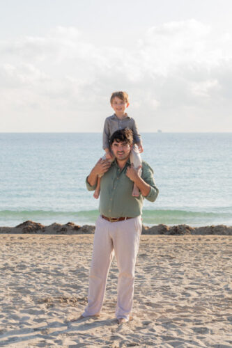 father carrying son on shoulders at the beach