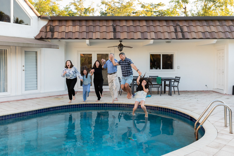 family jumping in the pool with clothes on