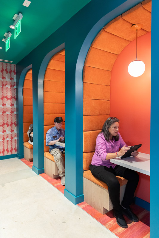 Row of booths where Senior Planet Miami members use tablets